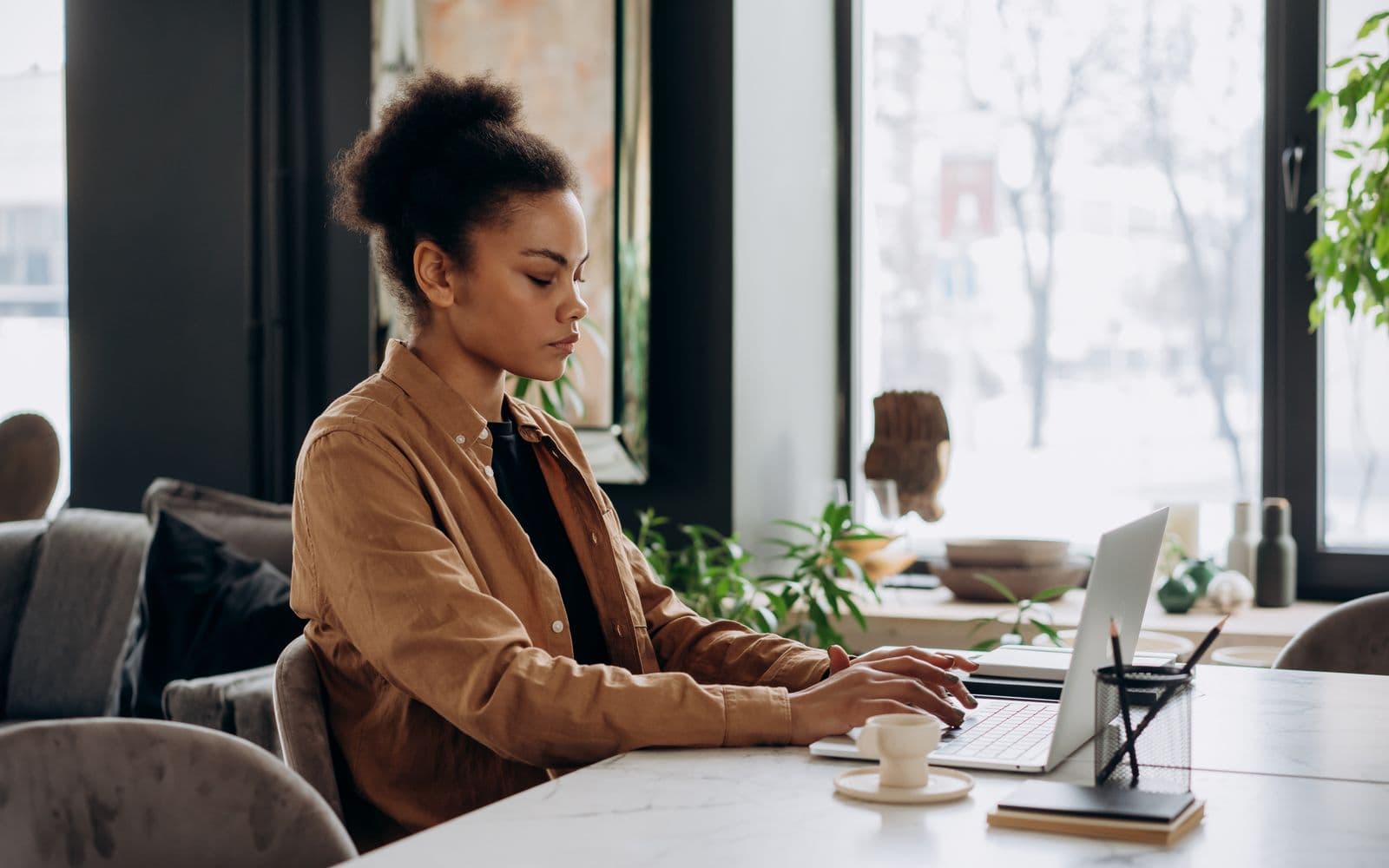 Woman working on a laptop beside a window