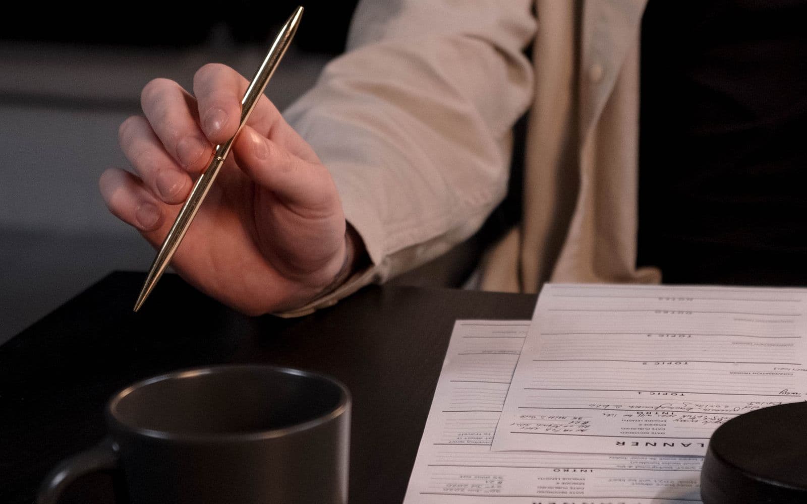 Hand holding a silver pen over office documents